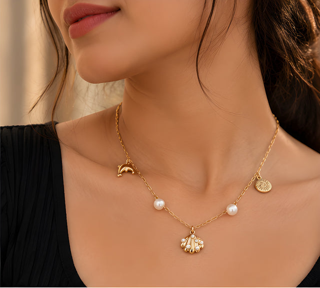 Vioras Ocean Charm Pearl Necklace in gold with pearls worn on a black top
