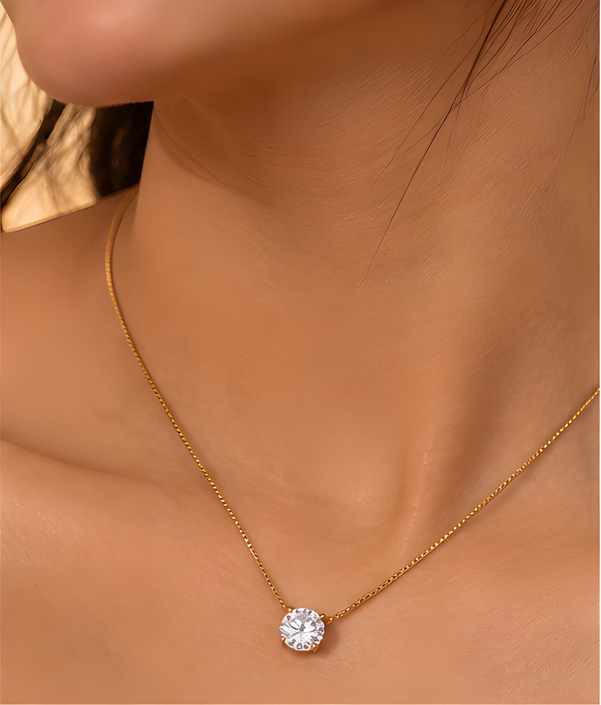 Close-up of Vioras gold solitaire pendant on neckline